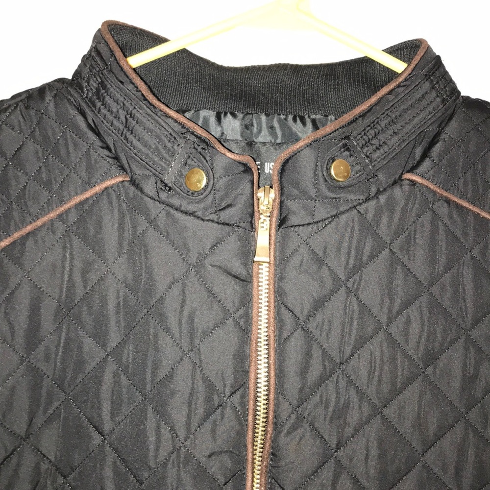 Black vest with brown piping and gold zippers.